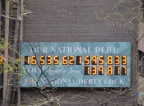 На фотографии изображен электронный табло, показывающее национальный долг США. Это табло расположено