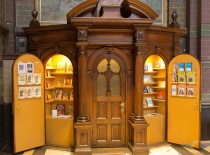 На фотографии изображен уютный деревянный киоск с книгами и сувенирами, расположенный в историческом
