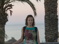 На фотографии изображена женщина на фоне пальм и моря, что создает атмосферу отдыха и расслабления.