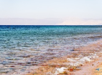 На фотографии изображен спокойный морской пейзаж с прозрачной водой и песчаным берегом. Видно, что э