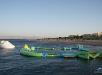 На фотографии изображен водный аттракцион в форме надувного комплекса, расположенный на спокойной во