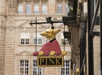 На фотографии изображена вывеска магазина с названием 'PINK', оформленная в виде звезды в красном па