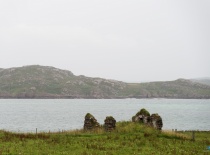 На фотографии виднеются руины старинного здания на фоне моря и холмов. Вероятно, это место находится