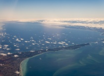 На фотографии запечатан вид с высоты на побережье, где море встречается с облаками. Возможно, это из