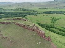 На фотографии изображен живописный ландшафт с зелеными холмами и скалистым обрывом, вероятно, распол