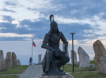 На фотографии изображена статуя воина, расположенная на фоне камней и флага России. Это место, вероя