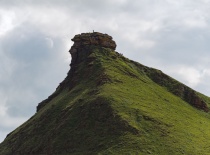 На фотографии изображена высокая зеленая гора с характерной скалистой вершиной. Возможно, это одно и