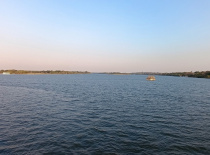 Спокойная река с лодкой на воде. На заднем плане видны зелёные берега и ясн