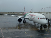 На фотографии изображён самолёт Boeing 787, стоящий на взлётно-посадочной полосе в аэропорту. Погода