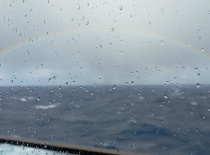 На фотографии видно море с дождевыми каплями на стекле, а над водой виден радуга. Это может быть сде