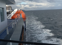 На фотографии вид с борта круизного судна, где видно море и след от корабля. Облака на небе создают